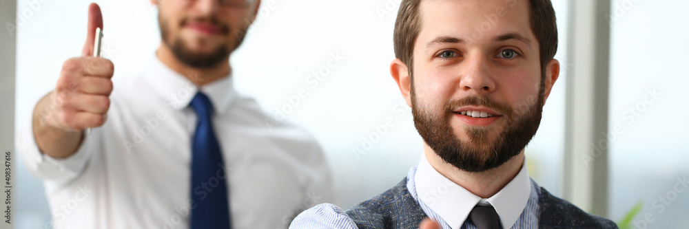 Happy successful businessmen showing okay symbol while posing at camera with window on the background. Teamwork and partnership concept Happy successful businessmen showing okay symbol while posing at camera with window on the background. Teamwork and partnership concept