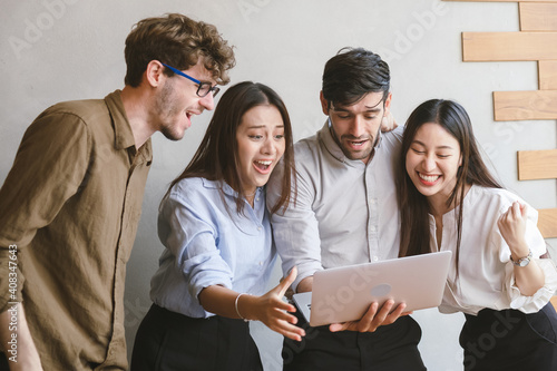 Cheerful,Amazed business people group,teamwork of young asian,caucasian having fun,happy in workplace after project is done,win while conference with partners on laptop.Celebrating success concept.