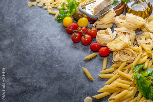 Mixed dried pasta selection on wooden background. composition of healthy food ingredients isolated on black stone background, top view, Flat lay.