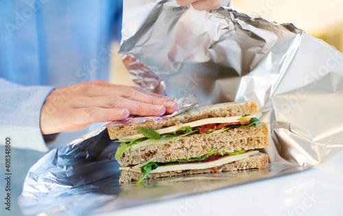 Close Up Of Woman Wrapping Sandwich In Non Reusable Aluminium Foil photo