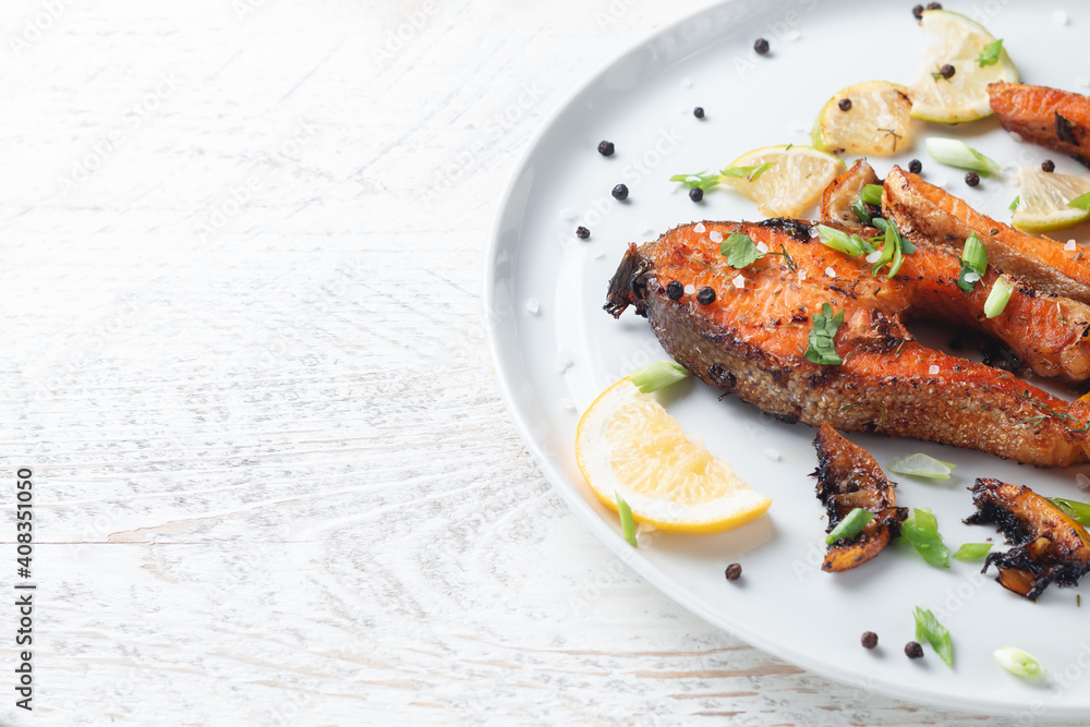 Grilled salmon steak with lemon, spices and lime in a white plate on a light wooden table. Deliciously cooked salmon fillet. Grilled salmon steak with lemon, spices and lime in a white plate on a light wooden table. Deliciously cooked salmon fillet.