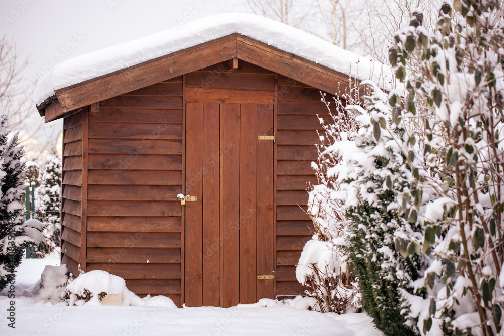 Obraz premium Drewniany domek altanka zimą w ogrodzie przykryta śniegiem