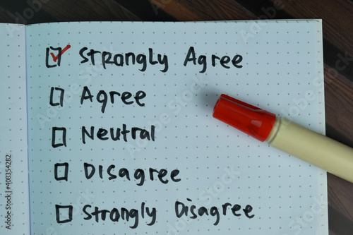 Strongly Agree write on a book and supported by additional services isolated on Wooden Table.