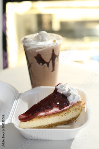 cherry cheesecake on a black background with reflection and flying icing sugar milkshake behind photo