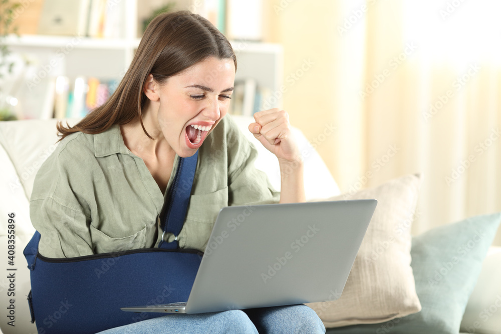 Excited disabled woman with broken arm reading news on laptop Excited disabled woman with broken arm reading news on laptop
