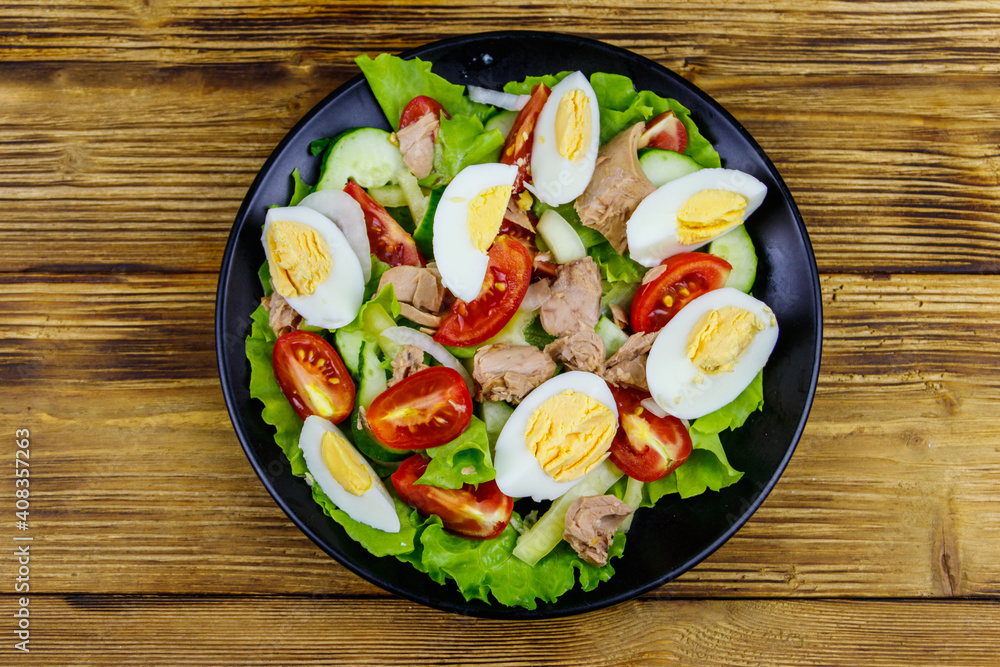 Tasty tuna salad with eggs, lettuce and fresh vegetables on wooden table. Top view Tasty tuna salad with eggs, lettuce and fresh vegetables on wooden table. Top view