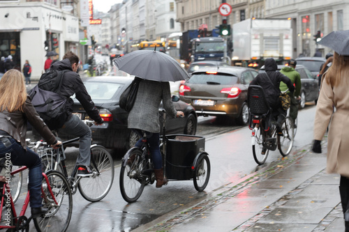 Bikes in the rainy city. Bike path in a European capital city. Bicycle traffic in Copenhagen. Reflection of cyclists in wet tarmac. Environmental friendliness concept