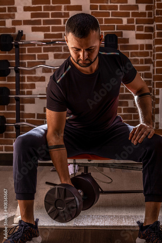 Cropped shot of fitness man doing concentration curls excercise working out with dumbbell in gym. Weight training concept. Young handsome man working out with dumbbells in a fitness gym.