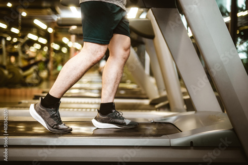 Legs of sportsman running in machine treadmill at fitness gym club