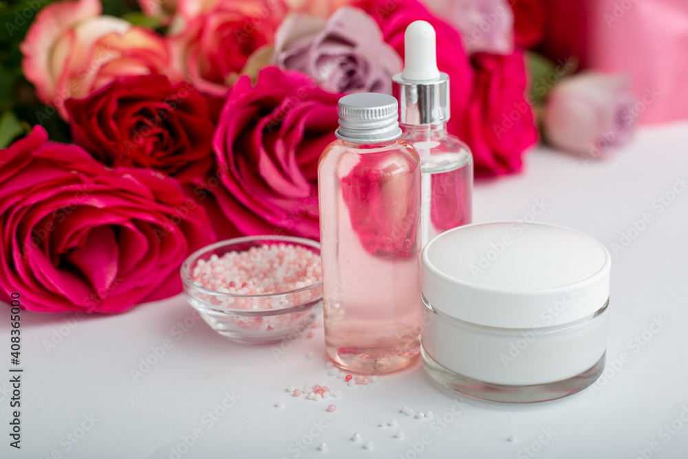 Glass cosmetic bottles, cream, serum, soap, oil on white table floral background. Flower red pink roses natural organic beauty product. Spa, skin care, bath body treatment. Set of cosmetics with rose Glass cosmetic bottles, cream, serum, soap, oil on white table floral background. Flower red pink roses natural organic beauty product. Spa, skin care, bath body treatment. Set of cosmetics with rose
