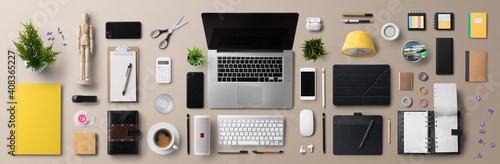 Flat lay top view office desk working space with laptop and supplies on gray background.