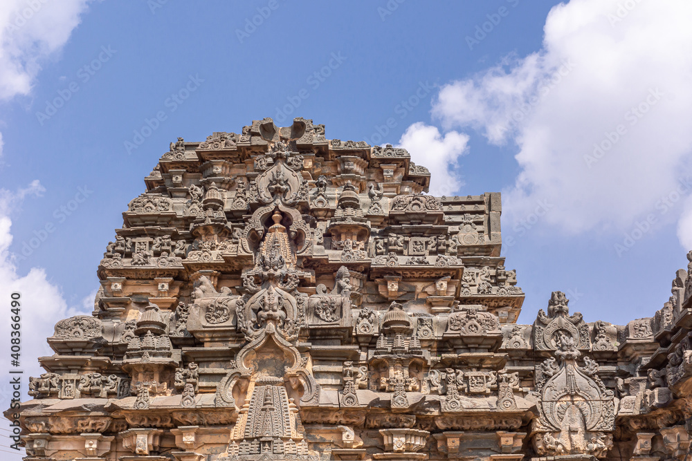 Lakkundi, Karnataka, India - November 6, 2013: Kasivisvesvara Temple. Sculpted brown stone vimanam on top of sanctum under blue cloudscape.