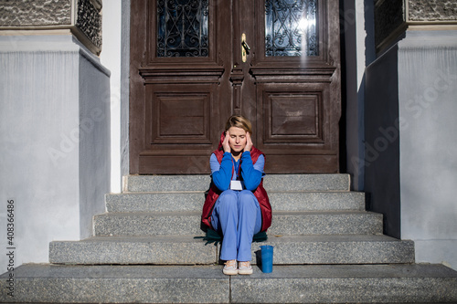 Tired woman caregiver or healthcare worker having a break outdoors, coronavirus concept. photo