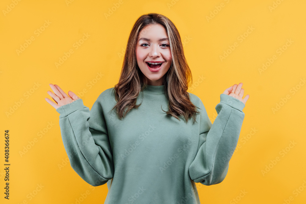 Attractive girl on a yellow background with a surprised expression looks at the camera and hands points to the sides with a place for the inscription Attractive girl on a yellow background with a surprised expression looks at the camera and hands points to the sides with a place for the inscription