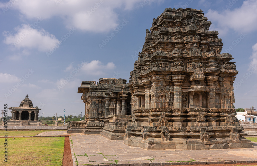 Lakkundi, Karnataka, India - November 6, 2013: Kasivisvesvara Temple in front and Nanneshwara temple in back under blue cloudscape and green lawn.