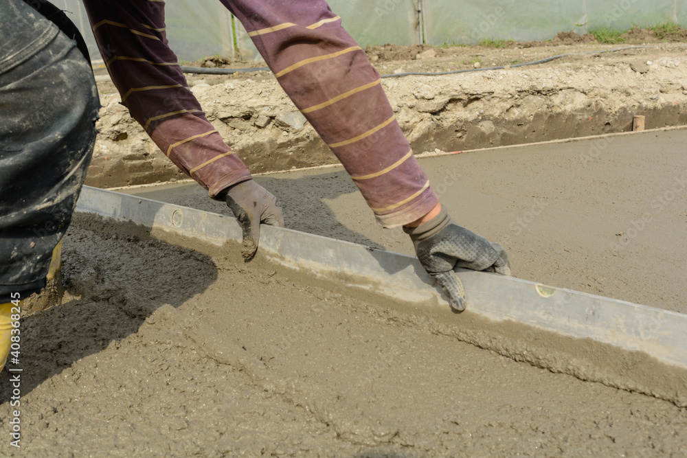 Fototapeta premium Bricklayer On Construction Site With Straightedge - Concrete
