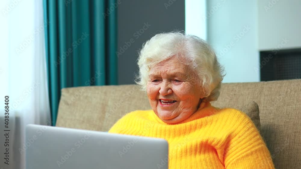 Portrait of old smiling lady looking at laptop and talking with family by online video call Portrait of old smiling lady looking at laptop and talking with family by online video call