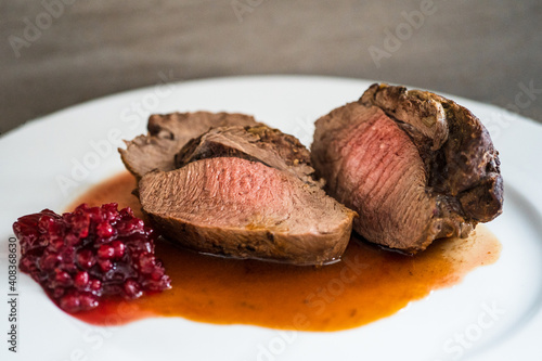 fresh cooking at home and ready to eat, delicious medium roasted game meat from the red deer calf with sauce on a white plate
