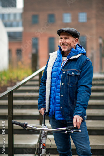 Happy senior man with bicycle outdoors in city, standing. © Halfpoint