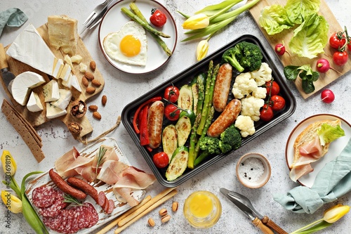 Breakfast food table. Festive brunch set, meal variety with grill platter, fried egg, croissant sandwich, cheese platter and desserts. Overhead view