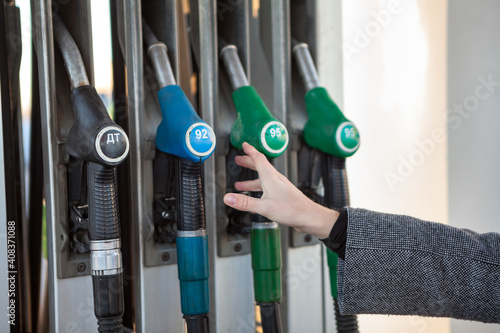 Caucasian female hand stretching to fuel nozzle with regular unleaded petrol, close up view