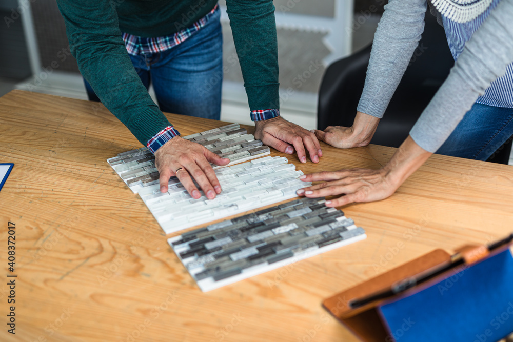 Fototapeta premium Man choosing ceramic tiles and utensils for his home bathroom and female seller helps him to make right decision