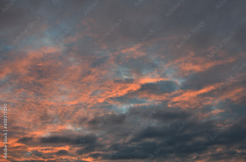 Beautiful dramatic sunset sky with colorful clouds. Summer evening abstract natural background in orange, gray and blue colors