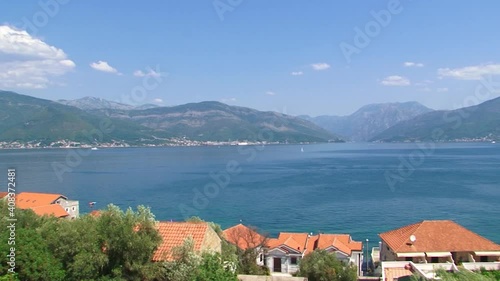 Panorama of Boka Kotorska Bay from town of Krasici. Blue sky, some clouds and still Adriatic sea water. Boats and coastline houses with mountains in back. photo