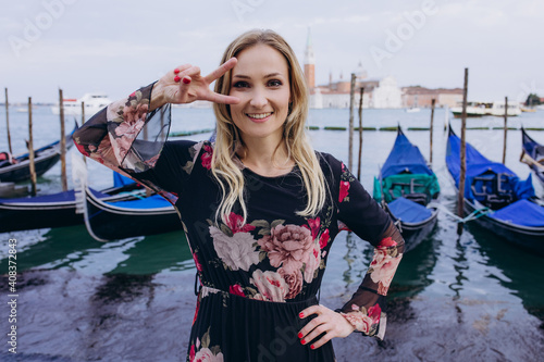 Portrait of a cheerful girl on the background of blue gondolas. A tourist travels around Venice.