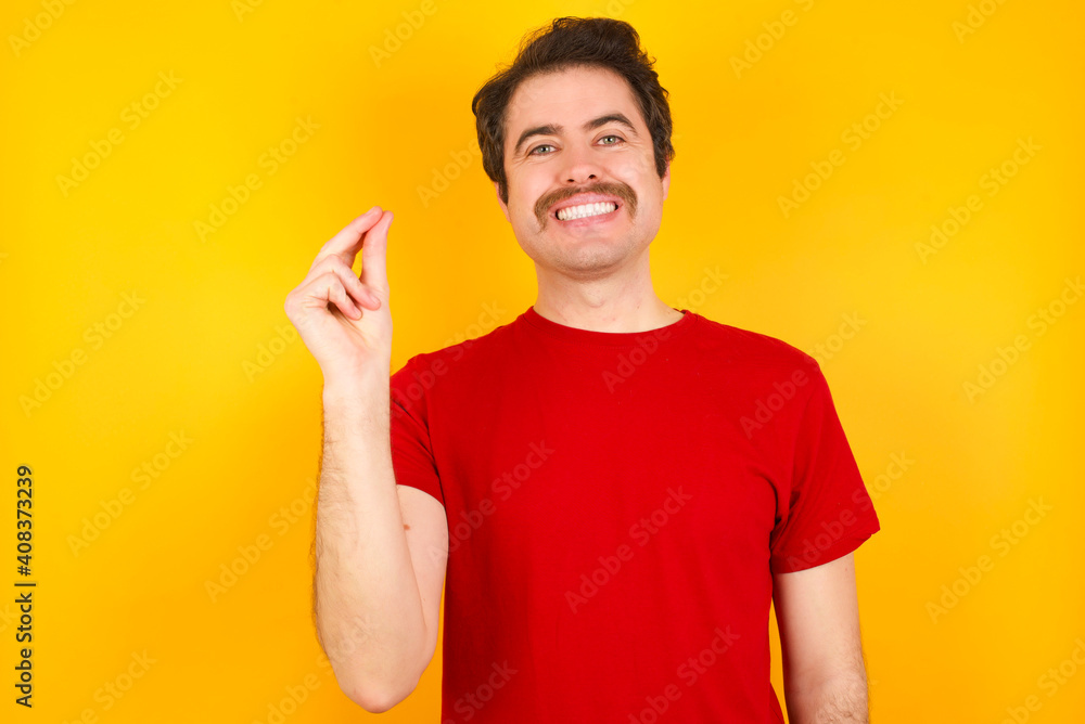 Young Caucasian man wearing red t-shirt standing against yellow background pointing up with hand showing up seven fingers gesture in Chinese sign language QÄ«. Young Caucasian man wearing red t-shirt standing against yellow background pointing up with hand showing up seven fingers gesture in Chinese sign language QÄ«.