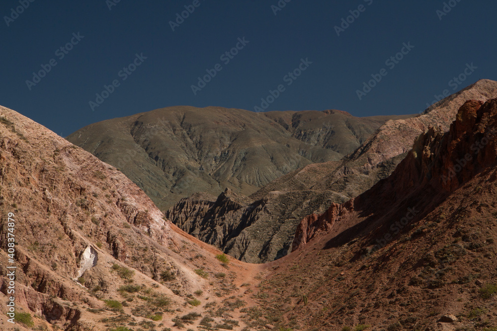 Arid landscape. View of the desert, rock minerals and colorful mountains under a blue sky. 
