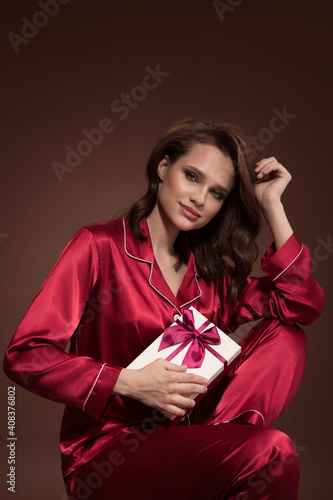 Portrait of a beautiful woman holding gift box in her hand. Brown background. © yuriyzhuravov