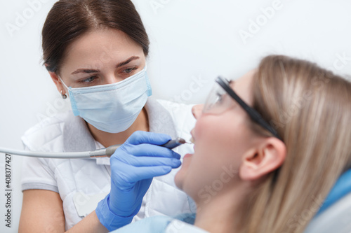 Close up of a professional dentist wearing medical face mask, examining teeth of patient