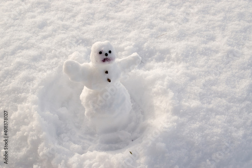 small snowman on snow  in a snowy winter garden