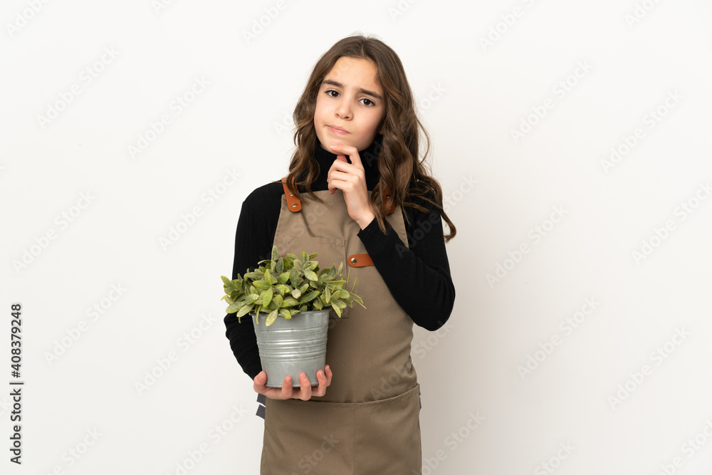 Little girl holding a plant isolated on white background thinking