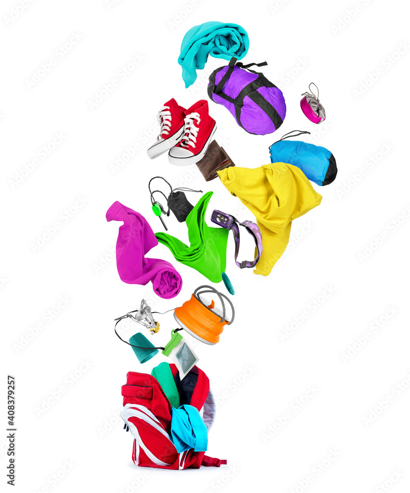 Various travel accessories flying out from red backpack, isolated on white background Various travel accessories flying out from red backpack, isolated on white background