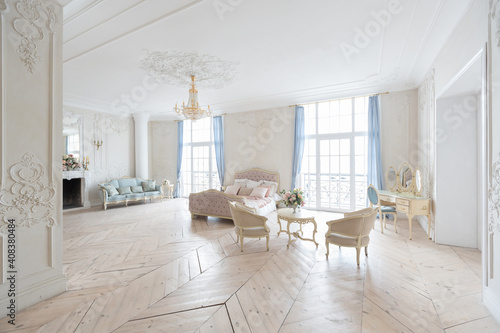 luxurious light interior in the Baroque style. A spacious room with a road chic beautiful furniture  a fireplace and flowers. plant stucco on the walls and light wood parquet