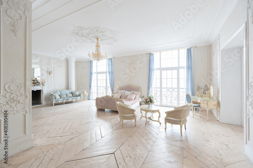 luxurious light interior in the Baroque style. A spacious room with a road chic beautiful furniture  a fireplace and flowers. plant stucco on the walls and light wood parquet