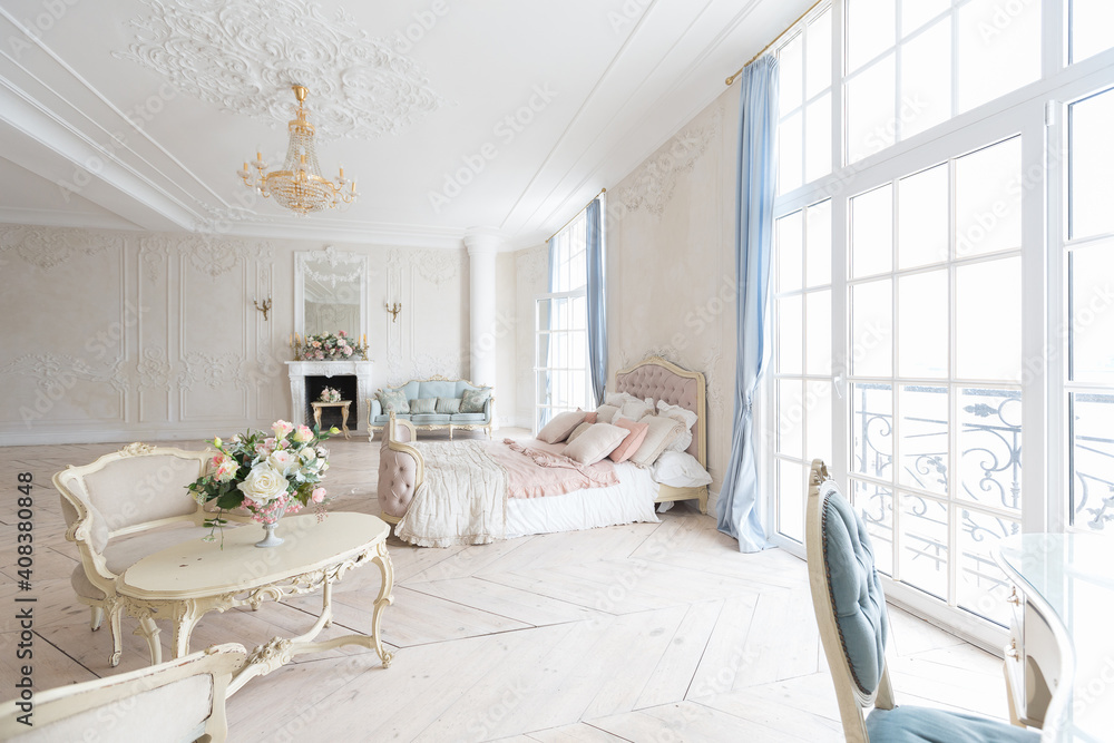 luxurious light interior in the Baroque style. A spacious room with a road chic beautiful furniture, a fireplace and flowers. plant stucco on the walls and light wood parquet luxurious light interior in the Baroque style. A spacious room with a road chic beautiful furniture, a fireplace and flowers. plant stucco on the walls and light wood parquet
