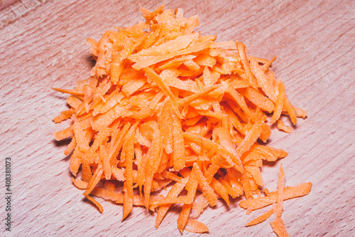 Sliced vegetables for cooking. Vegetables on a round wooden cutting board lying on the kitchen table. Grated carrots.