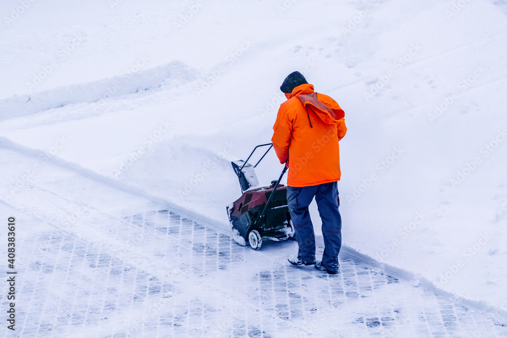 Man with motorized track drive snowblower clears  snow, a snowblower on a snowy road detail. Motor machine for removing wet, heavy snow. Snowthrower equipment.