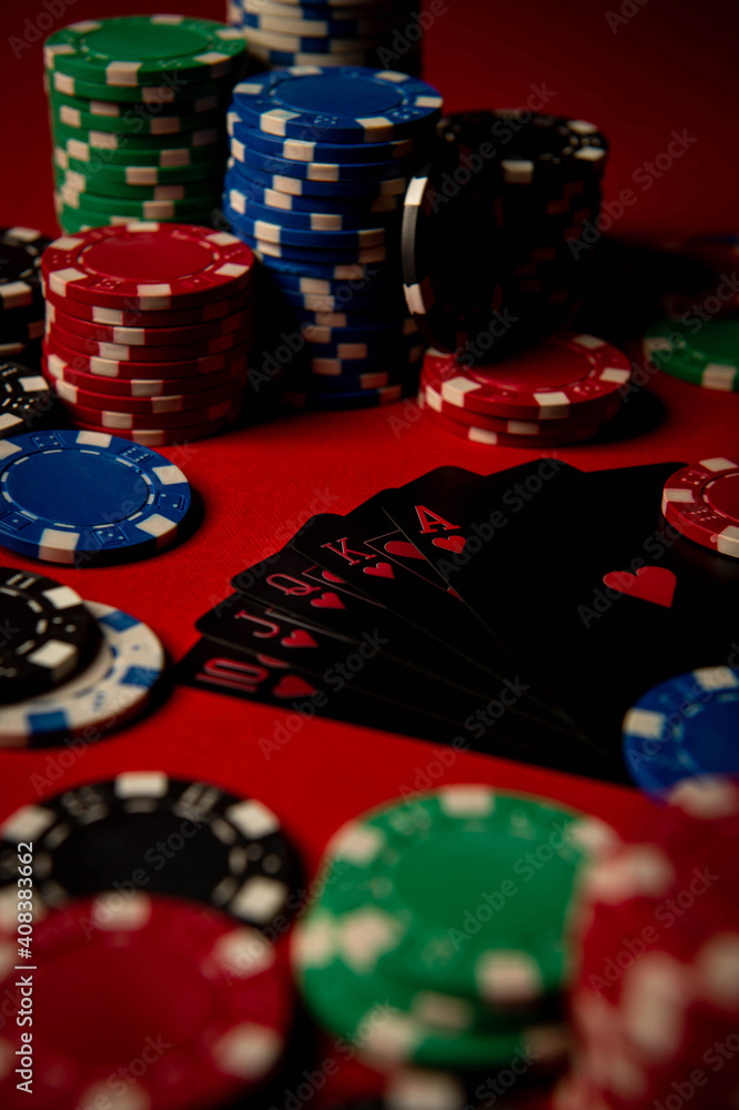 Game chips lie on the table against a red background. Game chips for betting in gambling. Poker chips. Playing cards. Game chips lie on the table against a red background. Game chips for betting in gambling. Poker chips. Playing cards.
