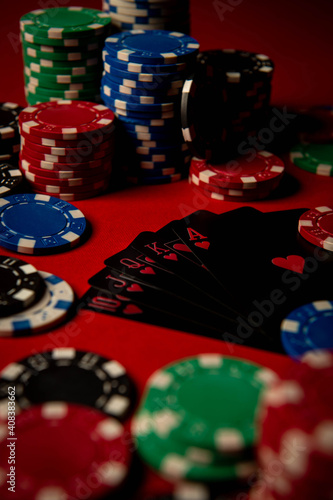 Game chips lie on the table against a red background. Game chips for betting in gambling. Poker chips. Playing cards.