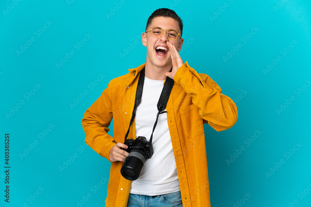 Naklejka premium Young caucasian photographer man isolated on blue background shouting with mouth wide open