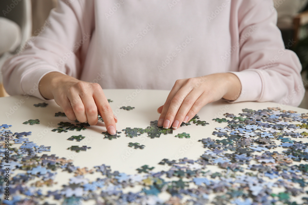 Young woman playing with puzzles at table, closeup Young woman playing with puzzles at table, closeup