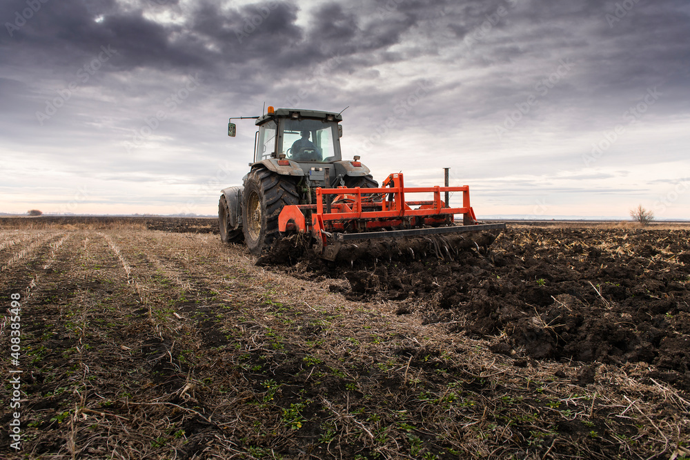 Fototapeta premium Tractor on the field during sunset.
