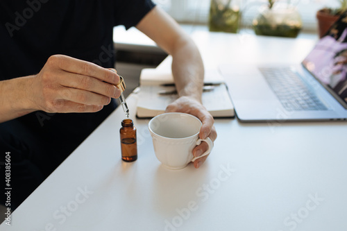 Vitamins and supplements. Hand holding pipette of Hemp herbal oil. Close up man uses CBD oil. Medical cannabis essence. Healthy lifestyle use medical essential tincture for better skin