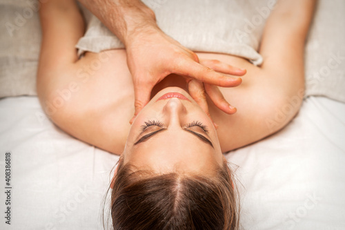 Chin or neck massage of a young woman by the hand of a male massage therapist in a spa salon