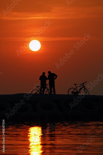 silhouette of friends riding a bike at sunset