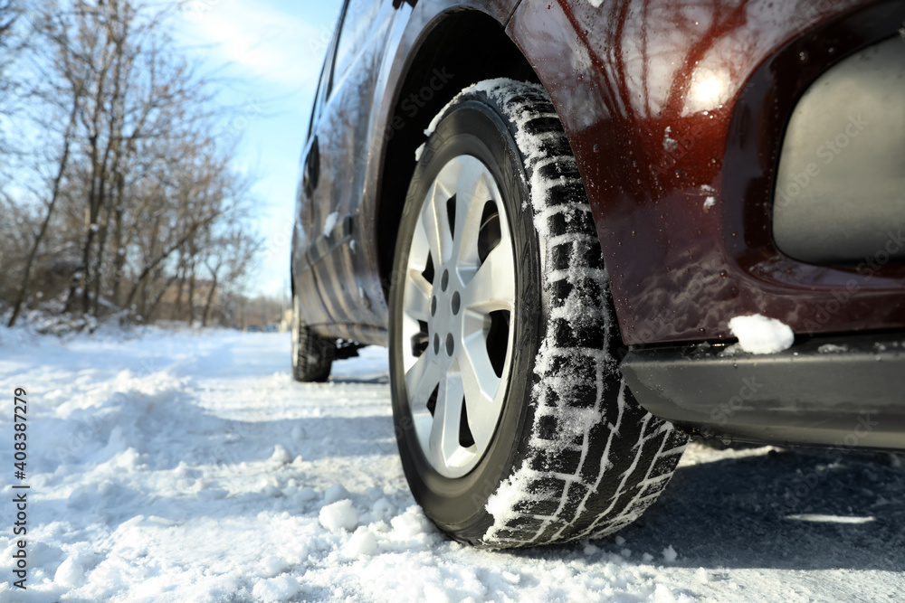 Car with winter tires on snowy road, closeup view. Space for text